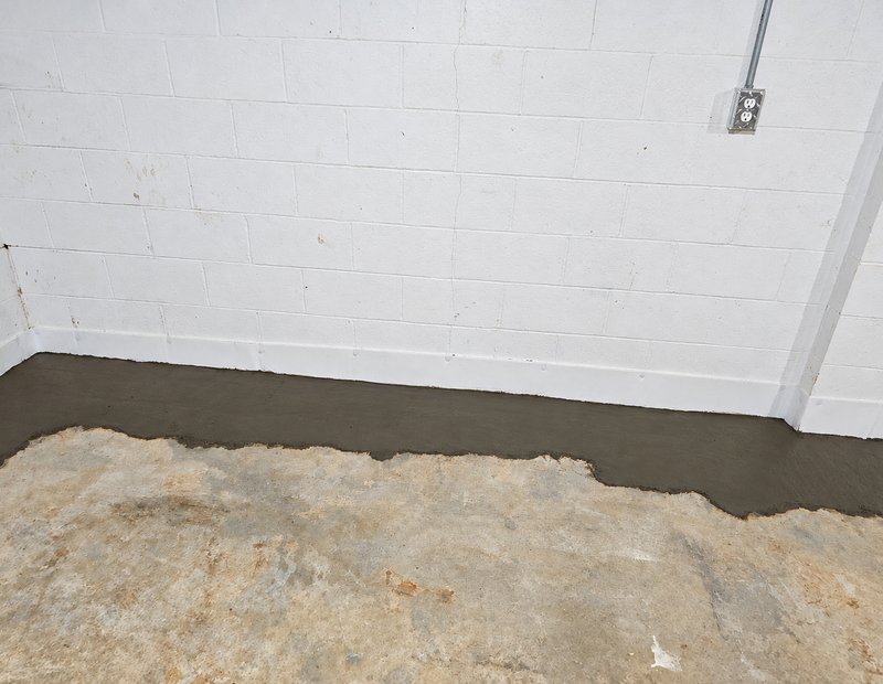 Interior basement waterproofing channel along a painted block wall